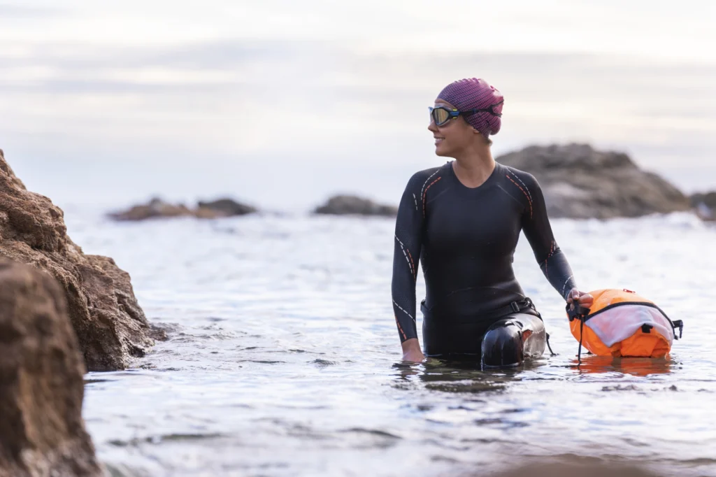 Outdoorschwimmerin im Neoprenanzug am Wasser
